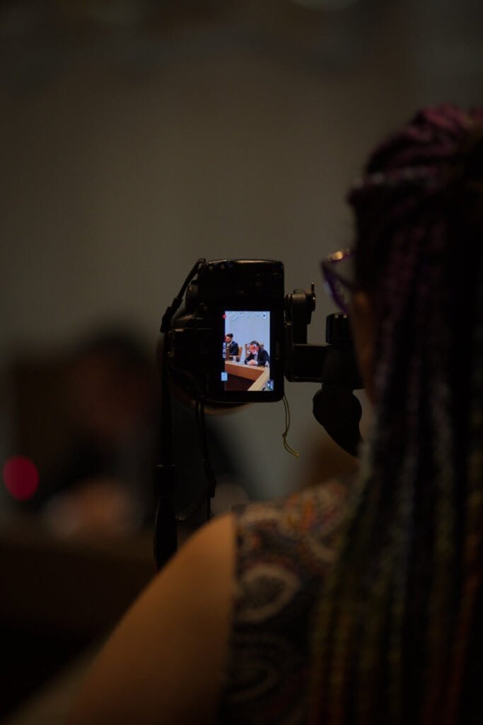 Person with colorful hair recording with a camera at an event.