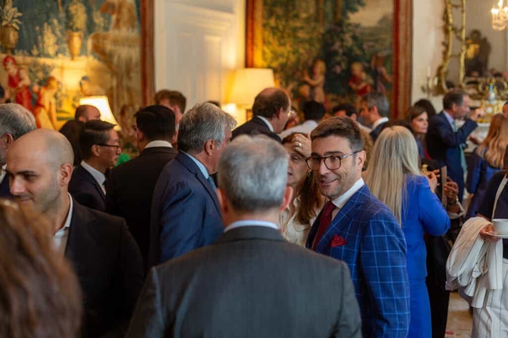 People engaging and talking at a formal social gathering in an elegant room.