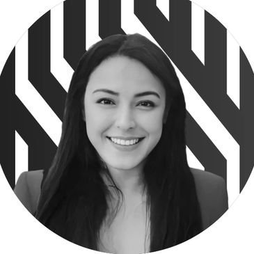 Smiling woman with long dark hair in front of a black and white geometric background.