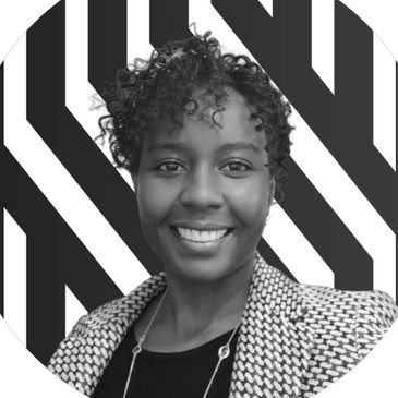 Smiling woman with short curly hair in front of bold black and white striped backdrop.